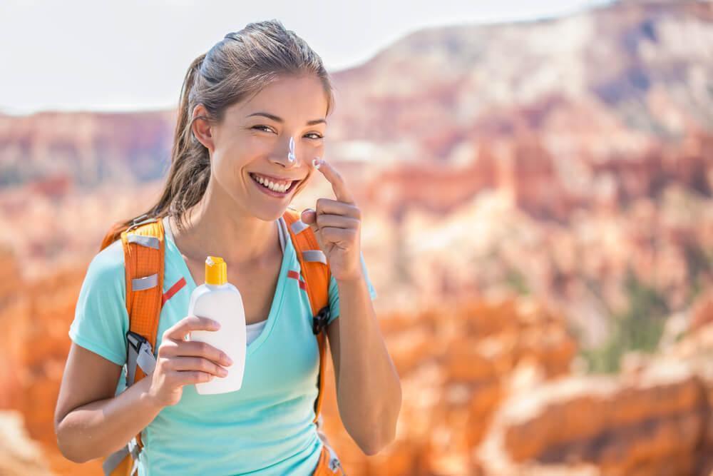 Woman applying SPF to nose while hiking