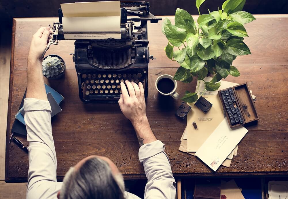 man using typewriter on wooden desk