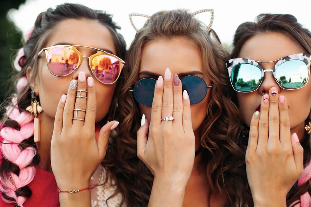 Three happy young woman showing off their nails