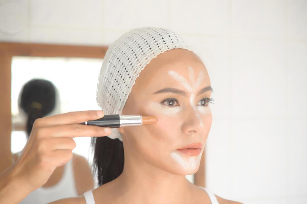 Woman applying contouring makeup to face