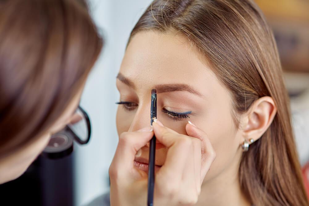 Makeup artist applying product to woman's eyebrow
