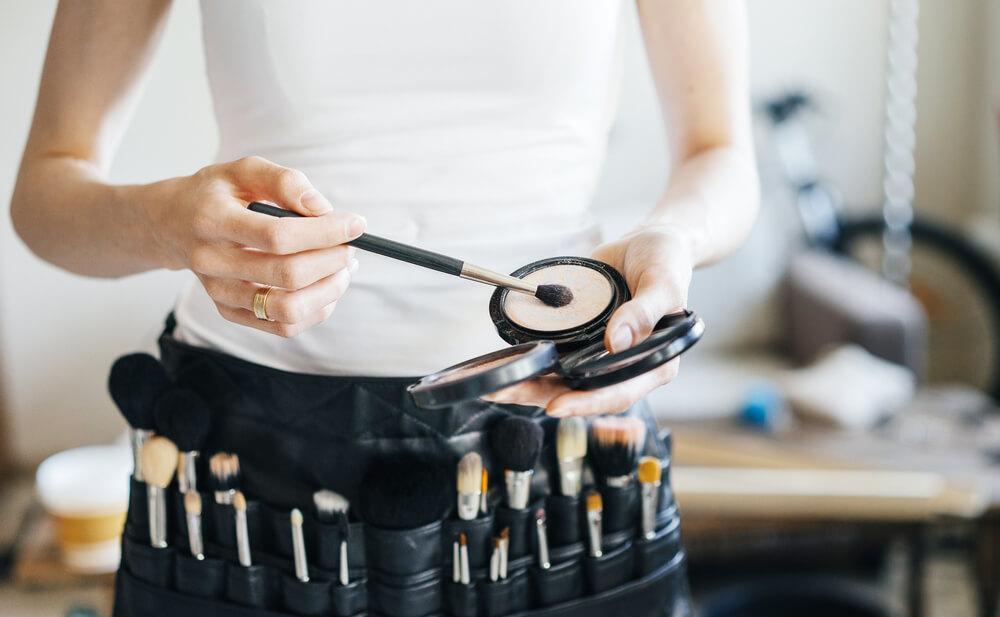 Makeup artist placing makeup brush into powder foundation