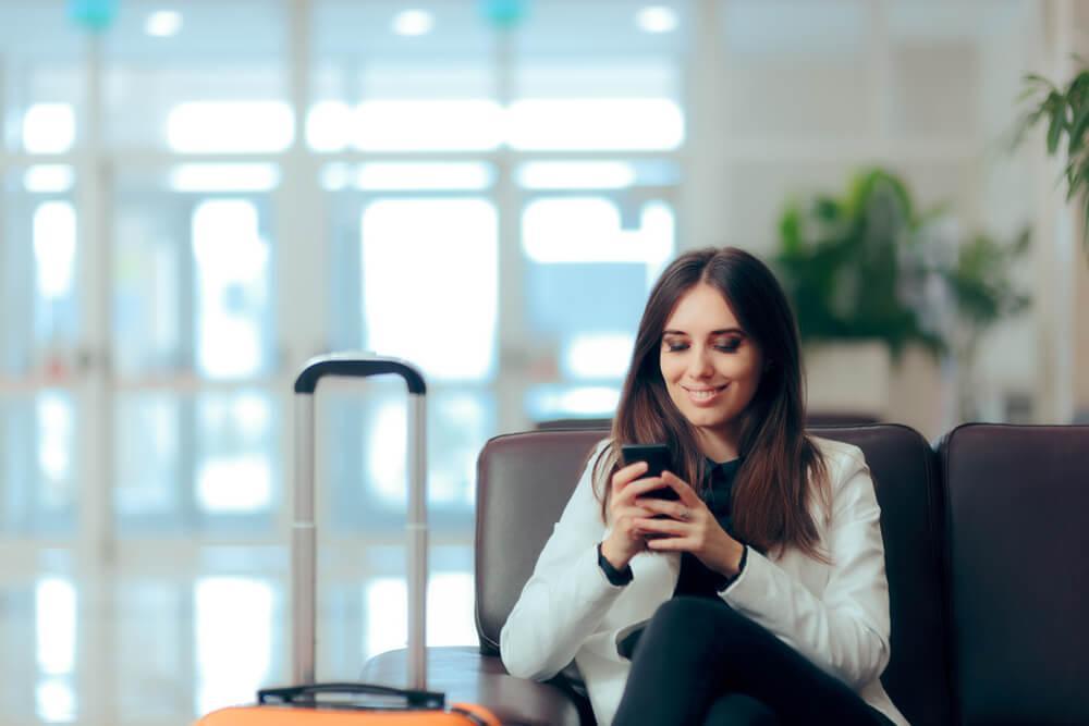 Woman sitting in airport looking at her phone