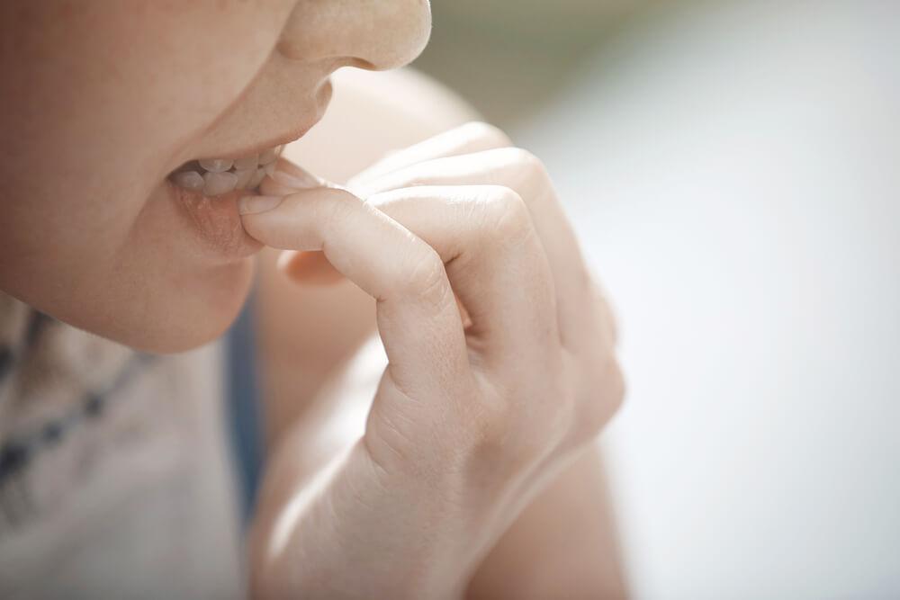 Close up of mouth chewing fingernails