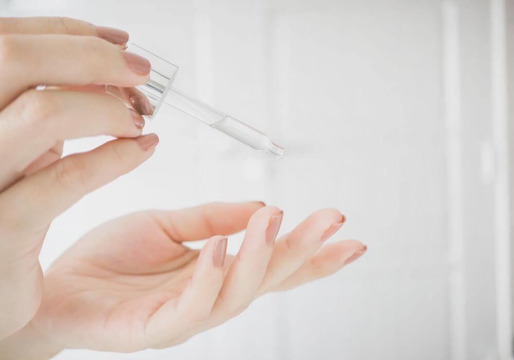 Hand applying serum to fingertip