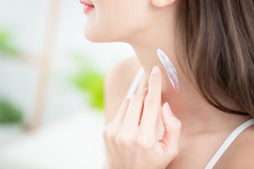 Woman applying cream to neck