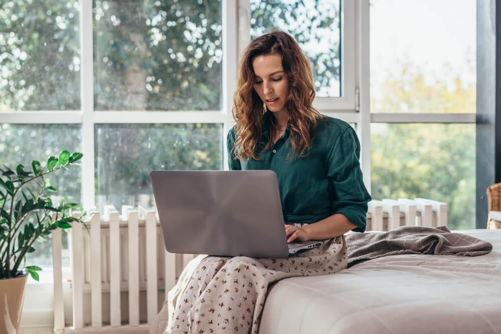 Woman using laptop on bed